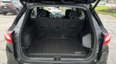 Open rear hatch of a black SUV, cargo area with a textured all-weather mat and folded rear seats visible in the back. The mat is labeled Equinox.