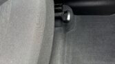 Car seat with a visible adjustment lever and track beneath, in a dark fabric interior.