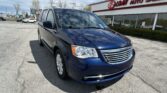Dark blue minivan parked diagonally in a car lot in front of a dealership building with an EZ Auto Sales sign in red letters.
