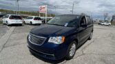 Blue SUV in the foreground at a car dealership lot with white vans and an EZ Auto Sales sign in the background on a cloudy day.