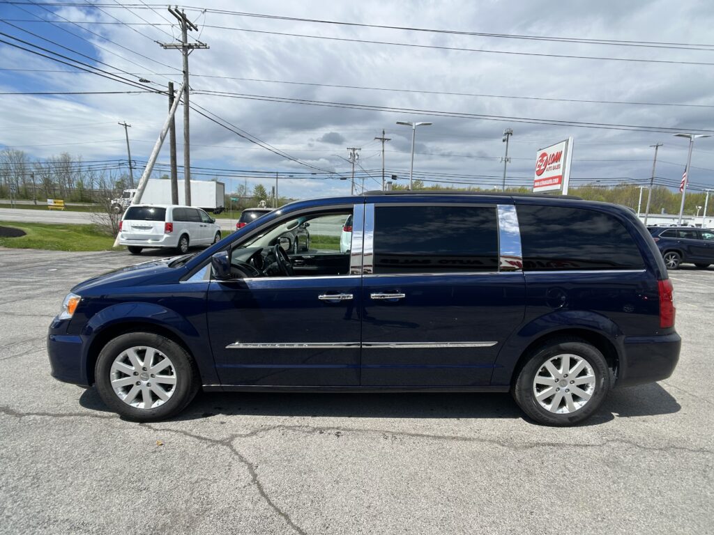 Dark blue SUV parked in a lot, side view with chrome trim, overhead power lines and a cloudy sky above.