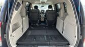 Open rear hatch showing a spacious cargo area in a minivan with the third-row seats folded flat and two captain chairs in front.