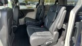 Interior of a minivan with black leather captain chairs and multiple rows of seating visible through the windows, showing a spacious cabin