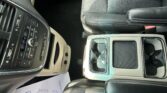 Center console area of a car interior with cup holders, leather seats, and climate control buttons on the left side of the image.