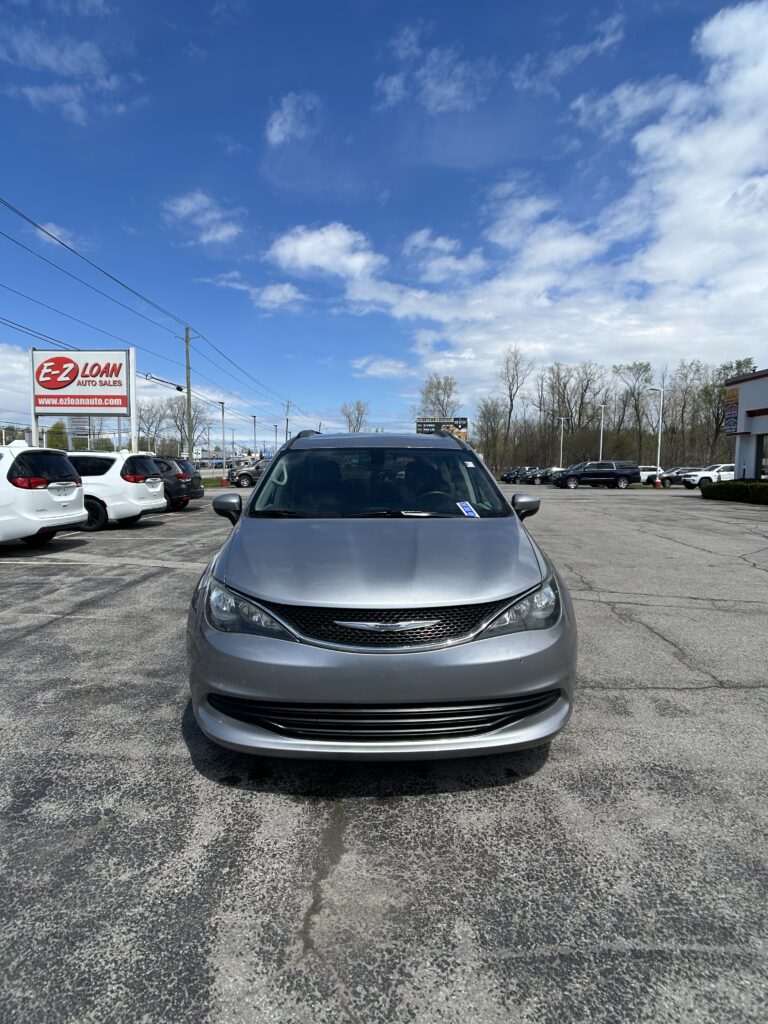 Front view of a silver car in a dealership lot with an EZ LOAN Auto Sales sign on the left.