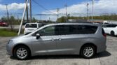 Silver minivan parked in a lot with power lines and a blue sky background.