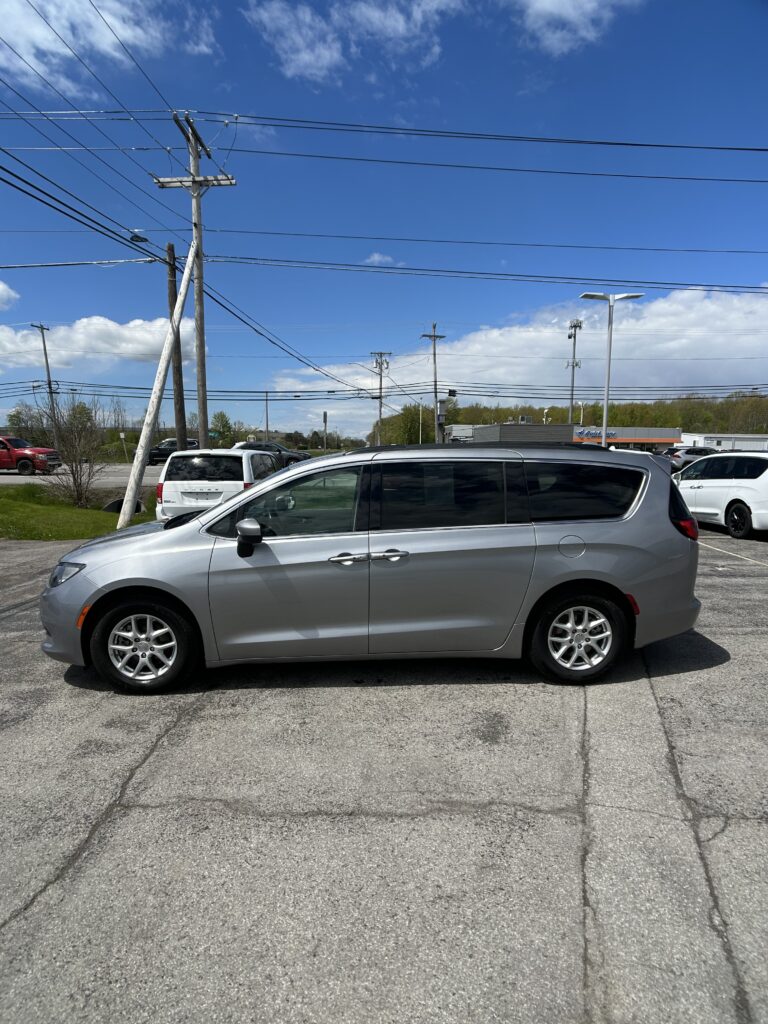 Silver minivan parked in a lot with power lines and a blue sky background.
