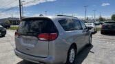 Rear view of a silver minivan parked in a lot under a bright blue sky with power lines overhead.