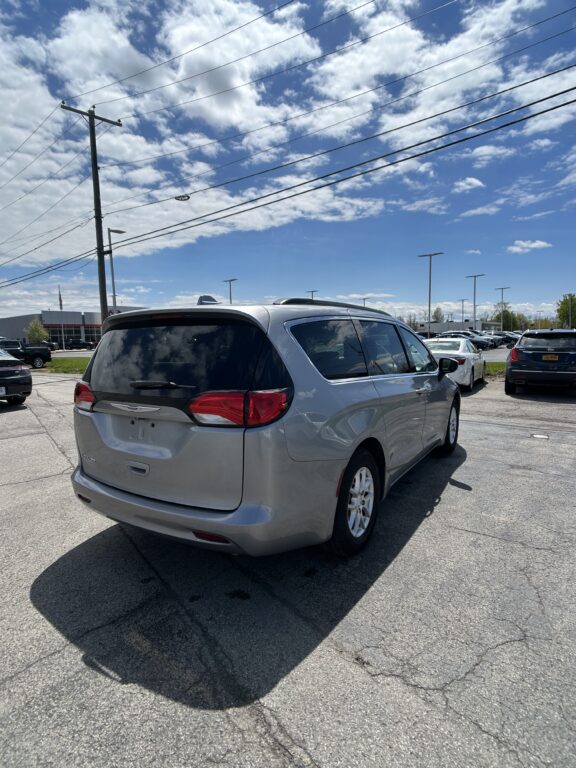 Rear view of a silver minivan parked in a lot under a bright blue sky with power lines overhead.