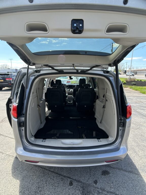 Open rear hatch showing spacious cargo area with folded third-row seats in a minivan/SUV; back row seating visible inside vehicle.