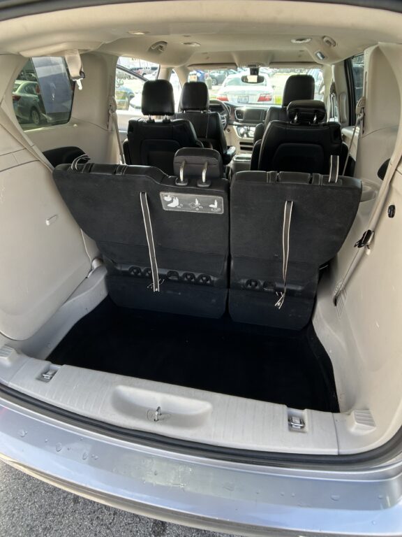 Rear cargo area of a minivan with third-row seats upright and black upholstery visible.