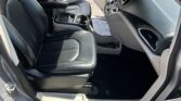 Open-door view of a car interior with black leather front seats, center console, and dashboard controls.