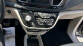 Driver's view of the car’s center console: touchscreen display flanked by air vents, climate controls, and gear selector with cupholders nearby.