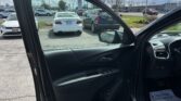 Driver-side car door open, view into the front seat with dashboard, in a parking lot under a cloudy sky