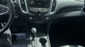 Interior of a car showing the center touchscreen, climate controls, gear shift, and cup holders from the passenger seat.