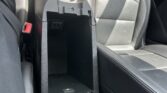 Open center console in a car, revealing cup holders and a large storage cubby between front seats.