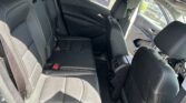 Back seat area of a black leather car with headrests and door panel, view out the open rear door window.