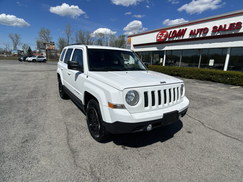 White Jeep SUV parked in a dealership lot in front of EZ LOAN Auto Sales on a sunny day.