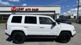 White Jeep Patriot SUV parked in front of E-Z Loan Auto Sales on a sunny day with a blue sky and power lines in the background.
