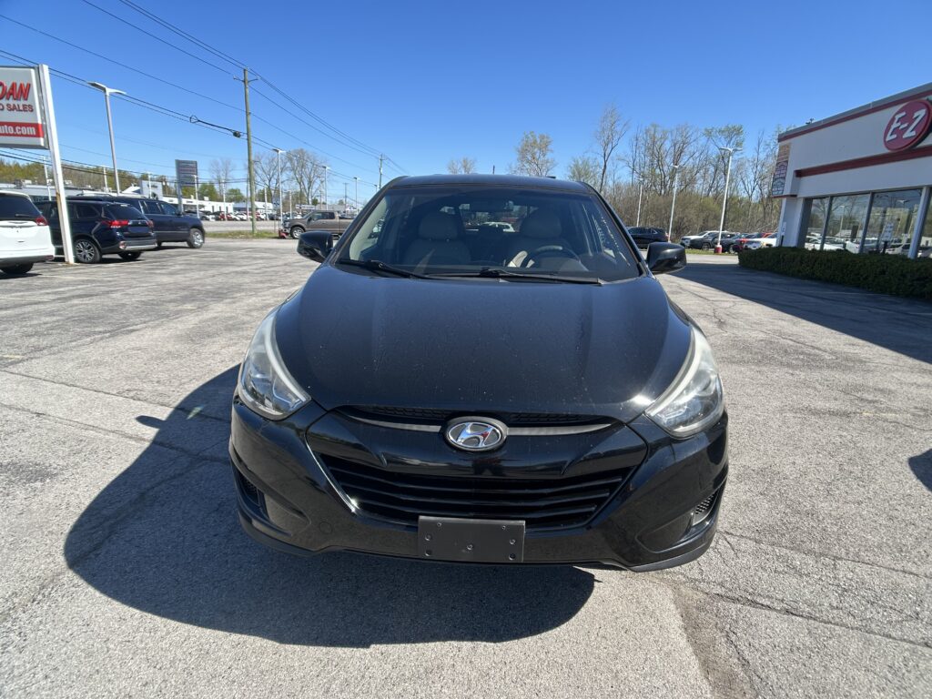 Front view of a black Hyundai car parked in a dealership lot on a sunny day with a clear blue sky.