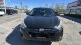 Front view of a black Hyundai car parked in a dealership lot on a sunny day with a clear blue sky.
