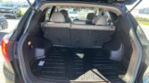 Open hatch of a black SUV showing an empty cargo area with the rear seats upright in a dealership parking lot.