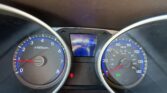 Close-up of the car's instrument cluster: left tachometer, right speedometer, and a blue digital center display showing mileage and range (eco mode visible).