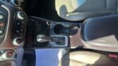 Interior of a car showing the center console, gear shifter, climate controls, and front seats bathed in sunlight.