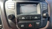 Car dashboard center display showing a rear-view camera view of a parking lot; to the right are buttons labeled CLOCK, SCAN, SETUP.