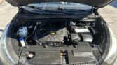 Open hood shows engine bay of a black car with battery and various hoses visible