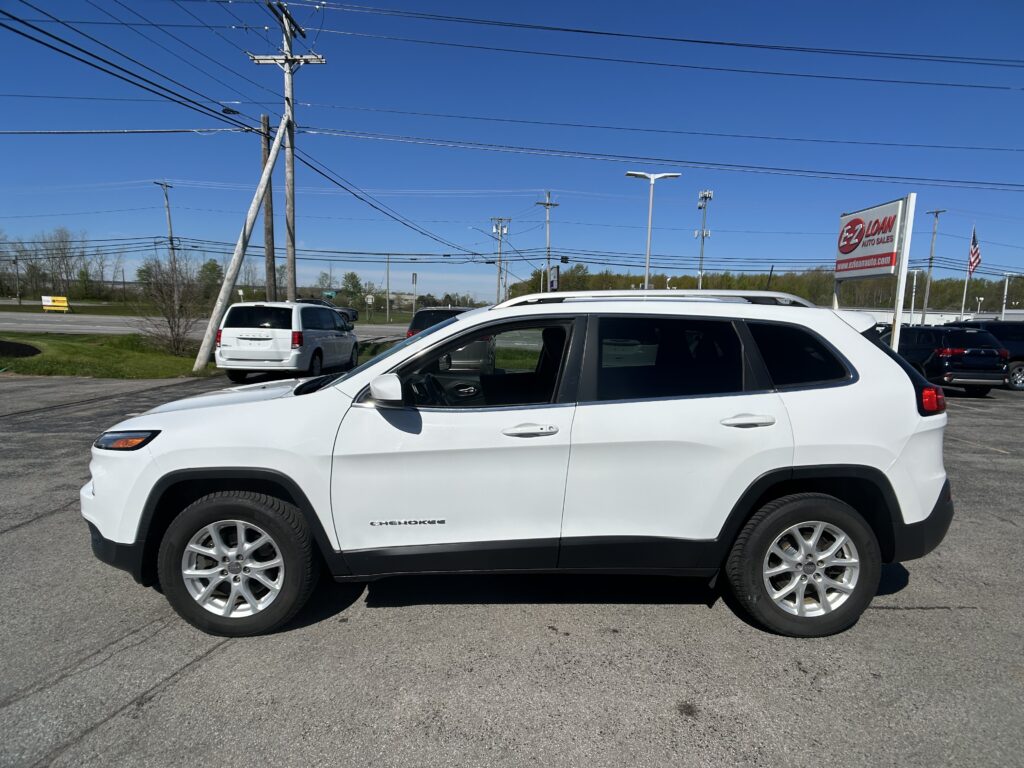 White Jeep Cherokee SUV in a parking lot with power lines and an EZ Loan Auto sign in the background
