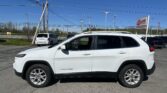 White Jeep Cherokee SUV in a parking lot with power lines and an EZ Loan Auto sign in the background
