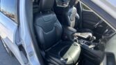 Front seats in a black leather Jeep, driver's door open and exterior car lot visible outside the vehicle window
