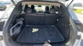 Open SUV trunk showing black rubber cargo mat and folded rear seats, sunny outdoor scene at a car lot