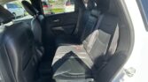 Rear interior of a car with black leather seats and three seat belts; parked cars visible through the windows outside.
