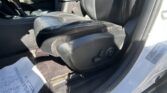Front passenger seat and center console of a car with papers on the floor and a visible seat belt buckle in sunlight.