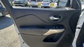 Interior car door panel with control buttons, side mirror, and a view of a parking lot filled with cars outside the window.