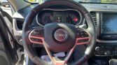 Driver's-eye view of a Jeep interior with steering wheel and center console; parking lot visible through the windshield.