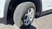 Close-up of a tire and alloy wheel inside the front wheel well of a white SUV