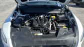 Front view of a car with the hood open, exposing the engine bay in a parking lot.