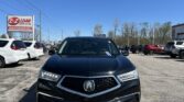Front view of a black Acura SUV in a car lot with an EZ Loan Auto Sales sign to the left and other vehicles in the background, under a clear blue sky.