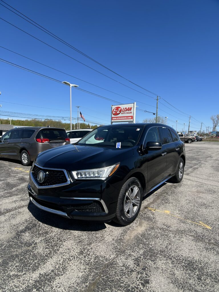 Black SUV in the foreground at EZ Loan Auto Sales lot under a clear blue sky with the dealership sign visible nearby.