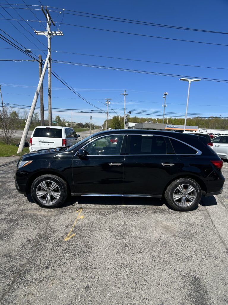 Black SUV in a parking lot with a leaning utility pole and many power lines against a blue sky.