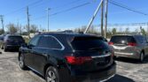 Rear three-quarter view of a black Mercedes SUV parked in a lot, with tall power lines and a utility pole against a clear blue sky.