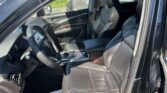 Open front passenger door reveals black leather interior with steering wheel and center console; dealership paper on the floor.
