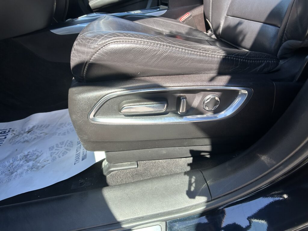 Leather car seat and center console with power recline/adjustment controls and chrome trim.