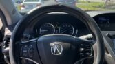 Driver's view from the seat showing the steering wheel and dashboard, with traffic ahead on a sunny road through the windshield.