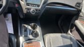 Interior of a car cabin focused on the center console with infotainment screen, climate controls, and gear selector visible.