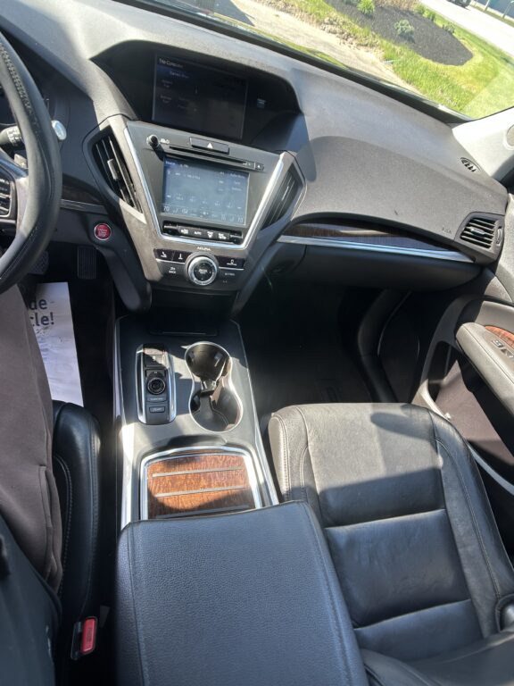Interior of a car cabin focused on the center console with infotainment screen, climate controls, and gear selector visible.