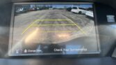 Car rear-view camera display showing parking guidelines (yellow lines) and a note to check surroundings.